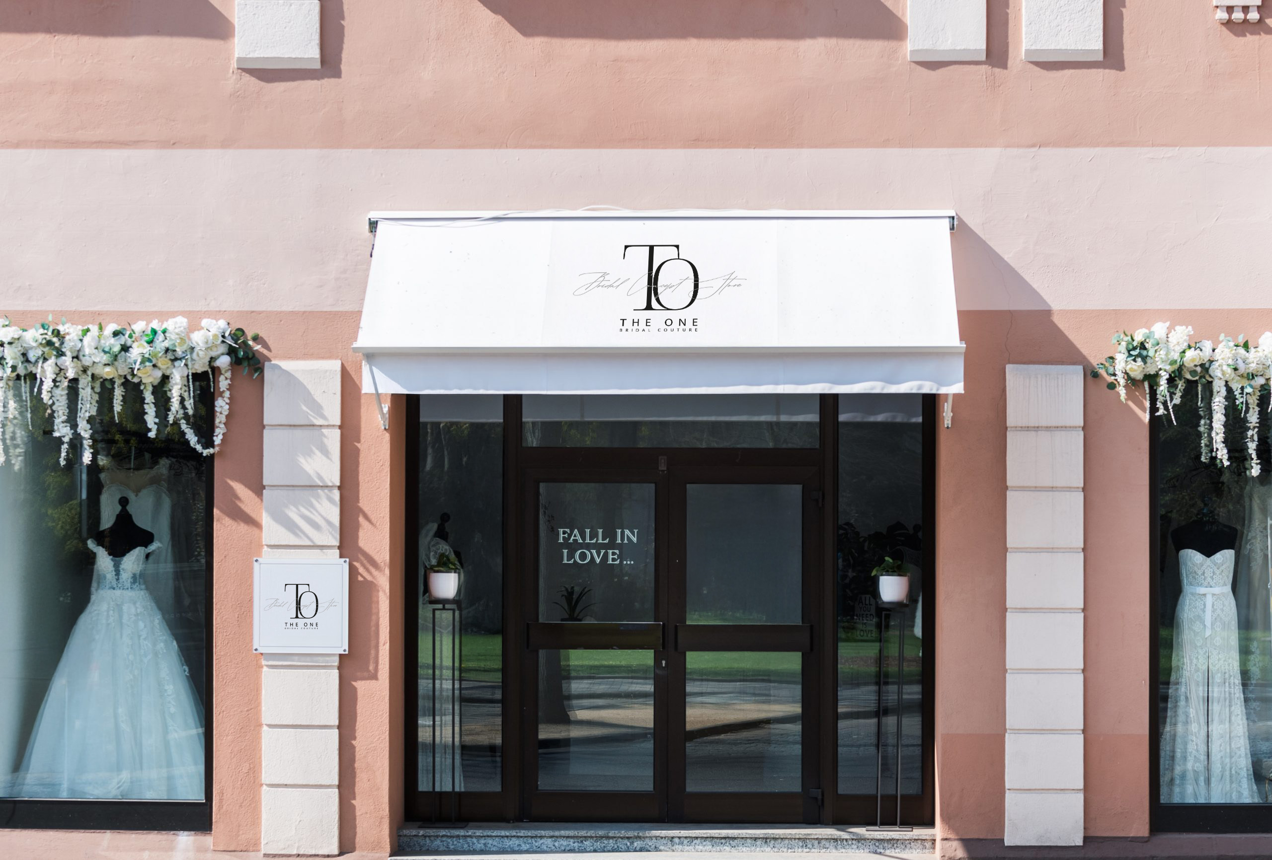 Ein Brautmodenladen-Eingang in Fulda mit weißer Markise, Glastüren und zwei wunderschönen Brautkleidern in den Schaufenstern.